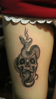 女性大腿上的骷髅蛇纹身