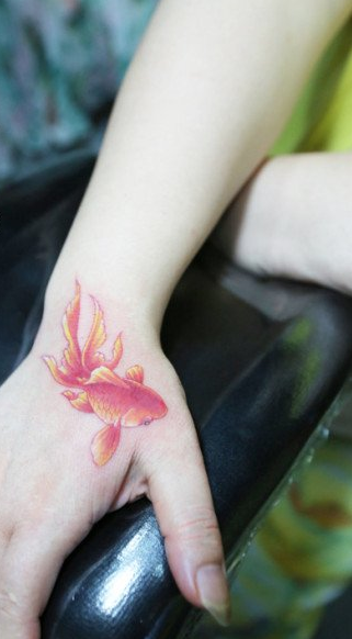 点击大图看下一张：女生手部潮流经典的彩色小金鱼纹身图案