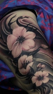 女性大臂上有着三朵花朵纹身