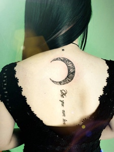 长发女生脊椎部的月亮与英文的纹身图案