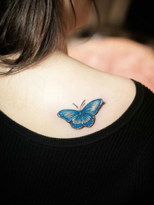 停留在女生后背的3d蓝蝴蝶纹身刺青