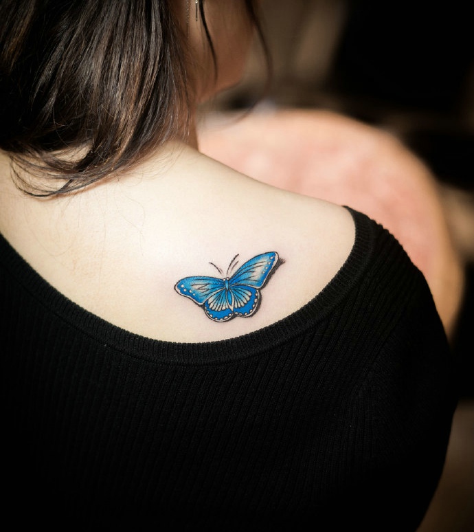 点击大图看下一张：停留在女生后背的3d蓝蝴蝶纹身刺青