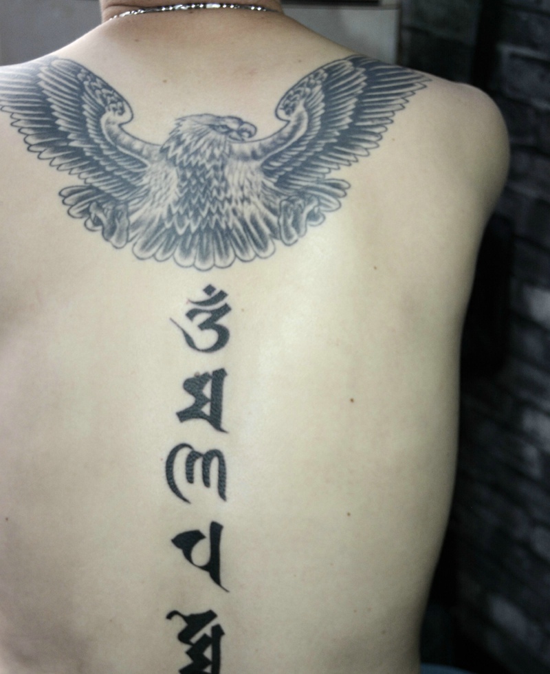 点击大图看下一张：翅膀与梵文结合的脊椎部纹身图片