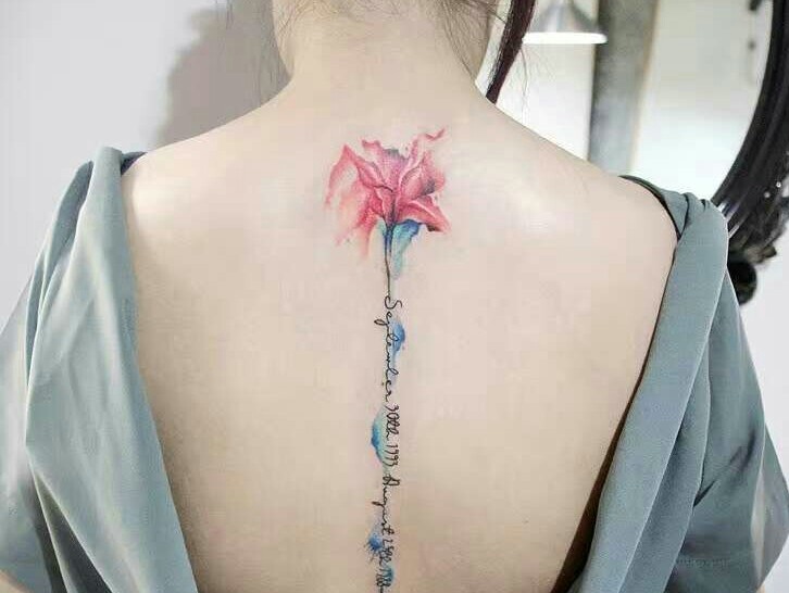 点击大图看下一张：百合花与英文一起的脊椎部纹身刺青