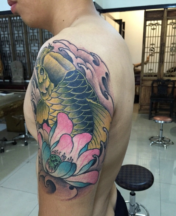 点击大图看下一张：莲花与金鲤鱼结合的大臂纹身刺青