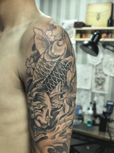 莲花与鲤鱼的大臂黑灰纹身图案