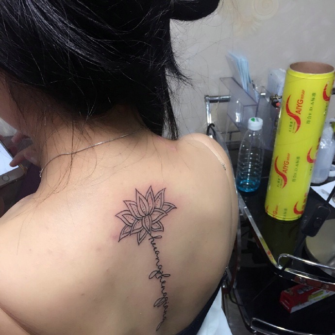 点击大图看下一张：处在脊椎部莲花与英文的纹身图案