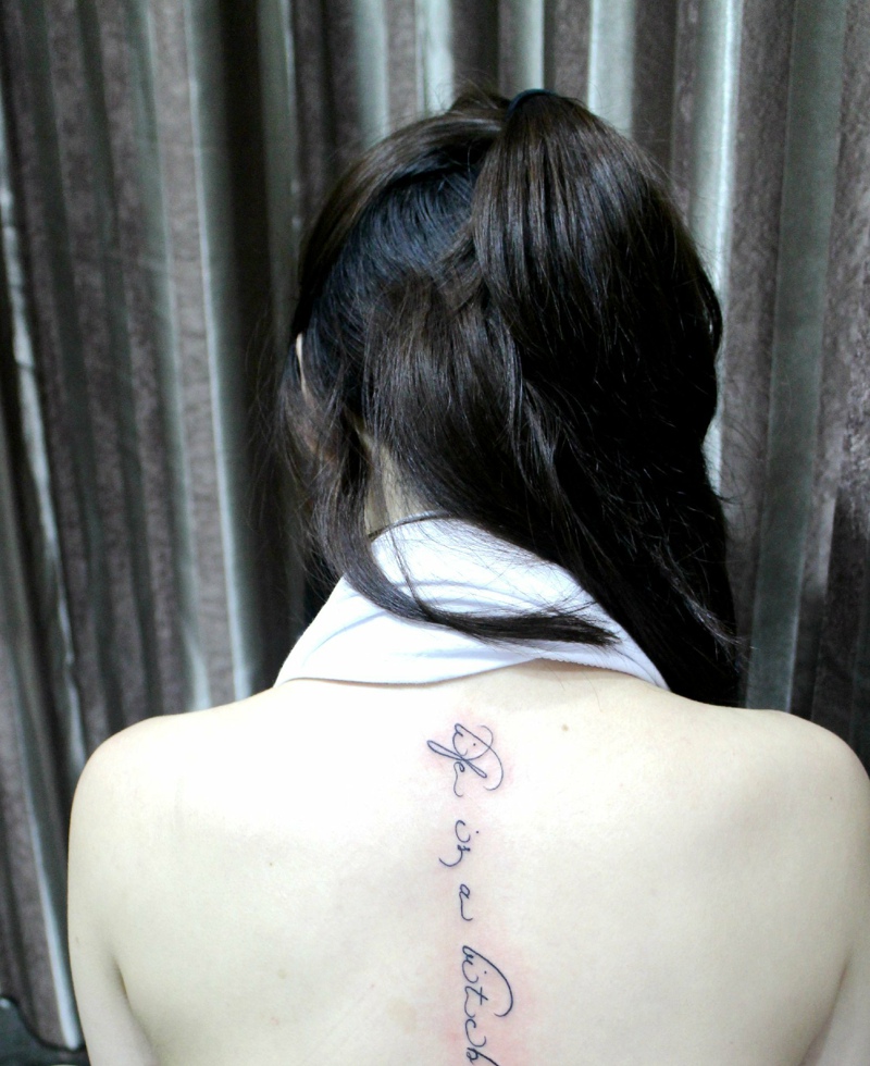 点击大图看下一张：长发女生脊椎部的时尚英文纹身刺青