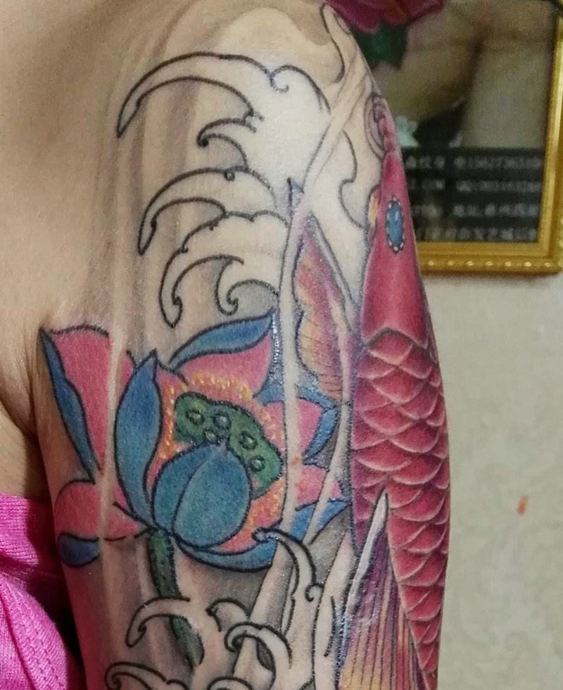 点击大图看下一张：莲花与红鲤鱼结合的大臂纹身图案