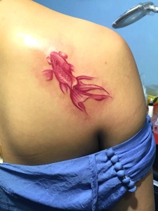一条小金鱼纹身落在女生肩膀下