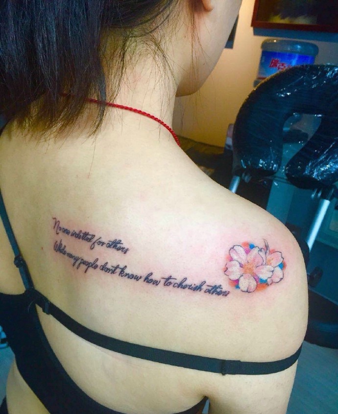 点击大图看下一张：女孩后背英文与花朵的纹身图片