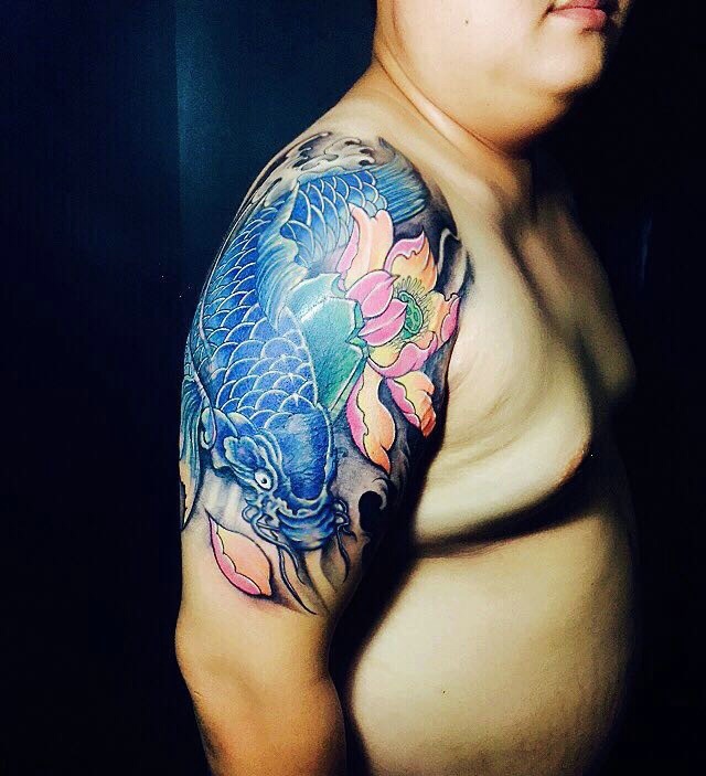 点击大图看下一张：莲花与蓝鲤鱼结合的大臂纹身图案