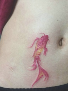 游在女生肚脐边上的小金鱼纹身图案
